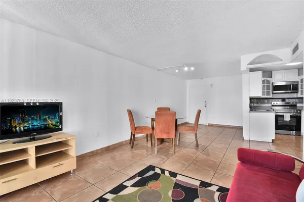 a living room with furniture a flat screen tv and kitchen view