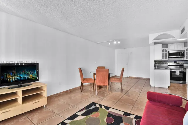 a living room with furniture a flat screen tv and kitchen view