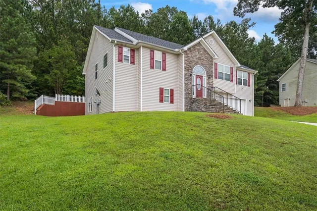 a front view of house with yard and trees in the background