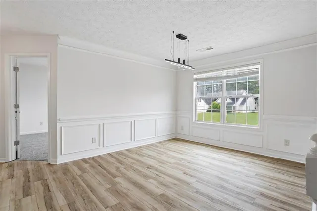 a view of an empty room with window and hardwood floor
