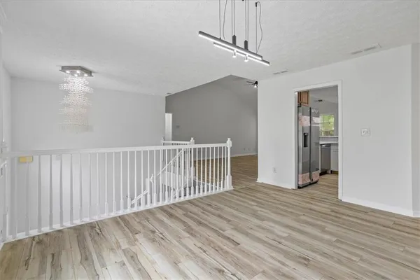 a view of a hallway with wooden floor and chandelier