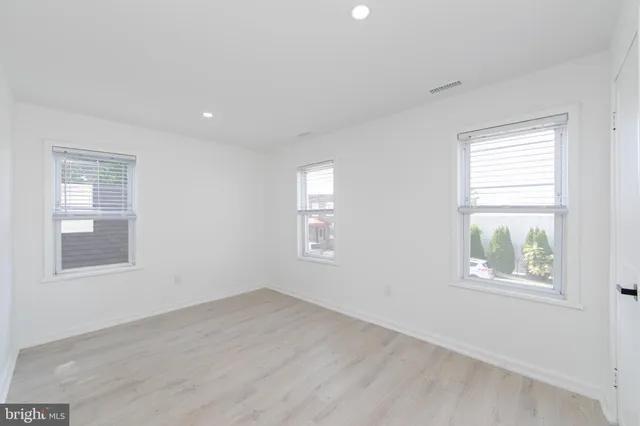 a view of an empty room with wooden floor and windows