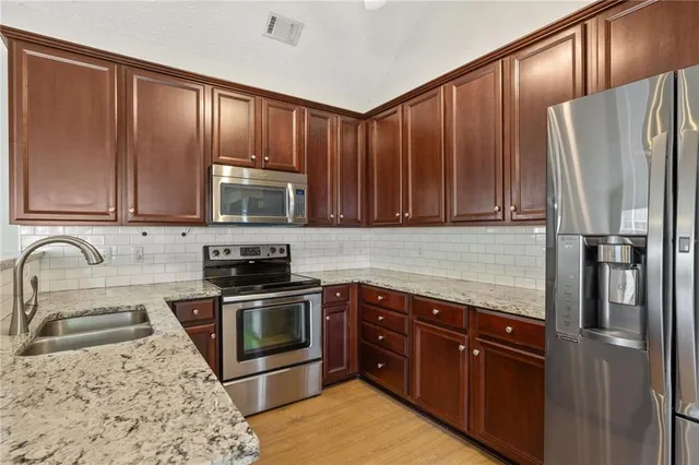 a kitchen with stainless steel appliances granite countertop a refrigerator stove and sink