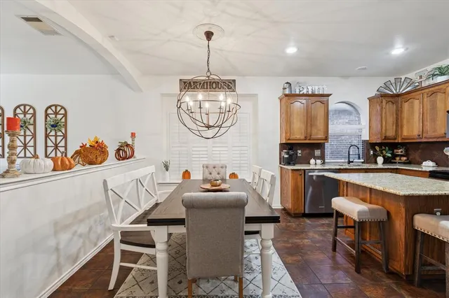 a kitchen with a refrigerator a stove a sink and a dining table with wooden floor