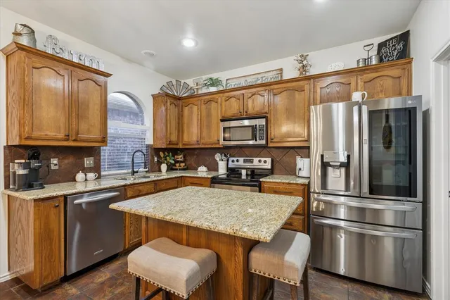 a kitchen with granite countertop stainless steel appliances a stove refrigerator sink and microwave