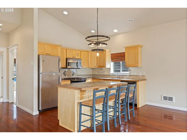 a kitchen with stainless steel appliances granite countertop a refrigerator a sink dishwasher a stove with wooden cabinets and floor