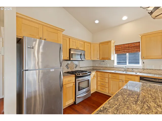 a kitchen with stainless steel appliances granite countertop a refrigerator a stove and a sink