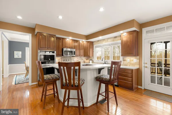 a kitchen with stainless steel appliances kitchen island granite countertop a refrigerator a stove a microwave oven a dining table and chairs with wooden floor