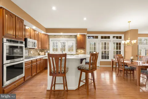 a kitchen with stainless steel appliances wooden floor dining table and chairs