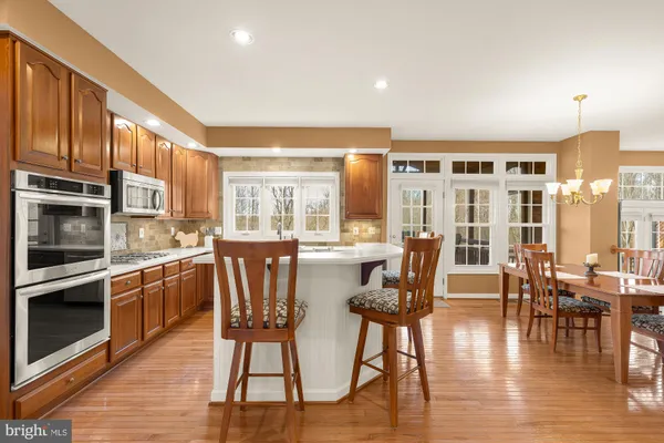a kitchen with stainless steel appliances wooden floor dining table and chairs