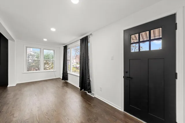 a view of an empty room with a window and wooden floor