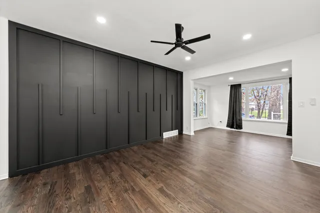 a view of a livingroom with a ceiling fan & windows