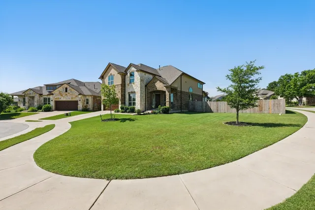a view of a house with a big yard plants and large trees