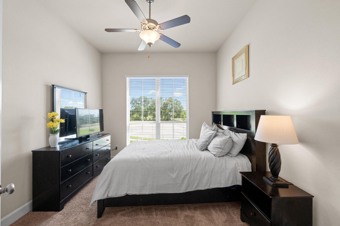 143 Pink Granite Boulevard Dripping Springs, TX 78620 - Photo 17 of 35 a bedroom with a bed and a flat tv screen on the dresser