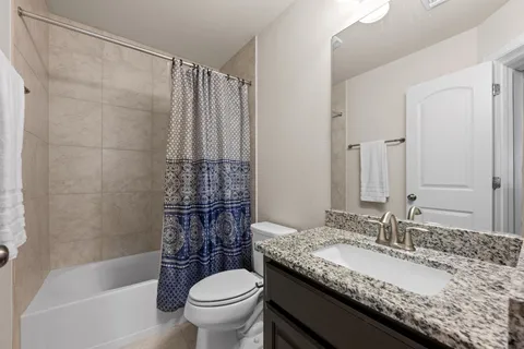 a bathroom with a granite countertop sink toilet and shower
