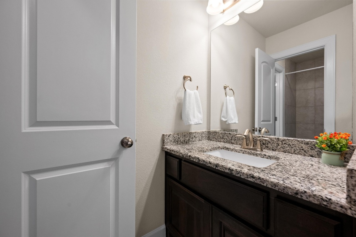 143 Pink Granite Boulevard Dripping Springs, TX 78620 - Photo 25 of 35 a bathroom with a granite countertop sink and a mirror