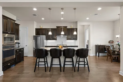 a kitchen with stainless steel appliances kitchen island granite countertop a refrigerator and chairs