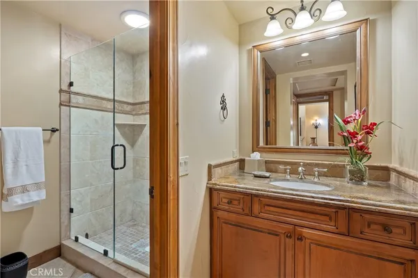 a bathroom with a granite countertop sink a toilet a mirror and shower