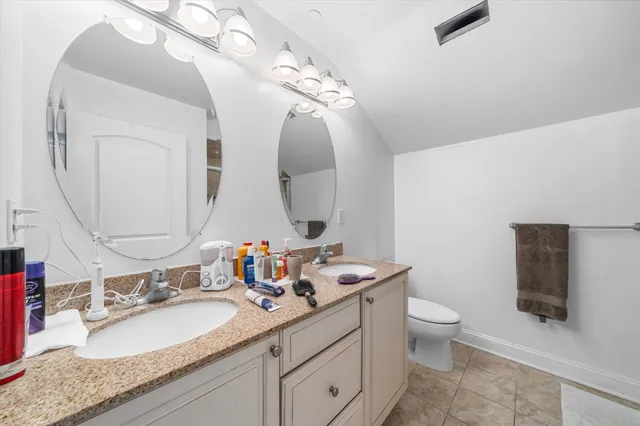 a bathroom with a granite countertop toilet sink and mirror