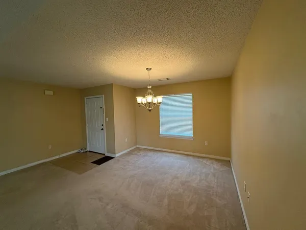 an empty room with windows and chandelier fan