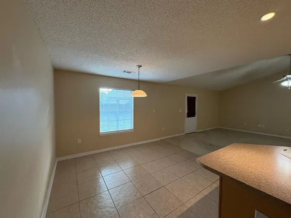 a view of an empty room with window and chandelier fan