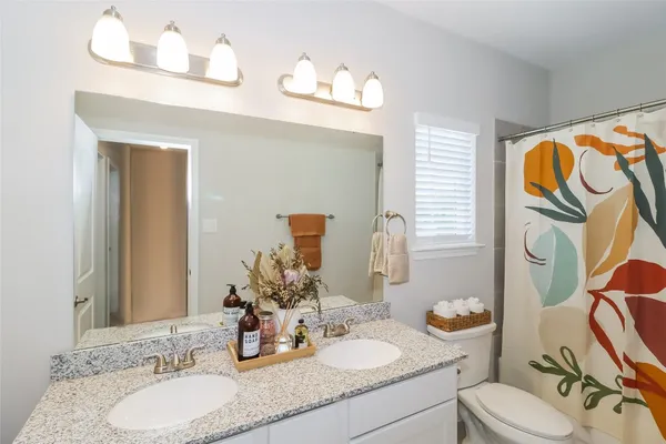 a bathroom with a granite countertop sink mirror and toilet