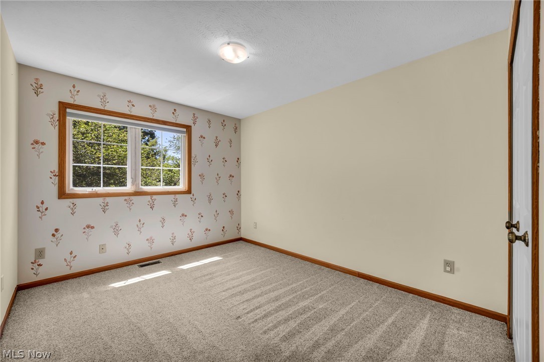 9842 Johnnycake Ridge Road Mentor, OH 44060 - Photo 18 of 40 Room with patterned wallpaper accent wall and a double-pane window