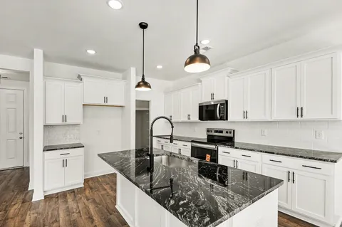 a kitchen with stainless steel appliances granite countertop a sink a stove top oven a counter space and cabinets