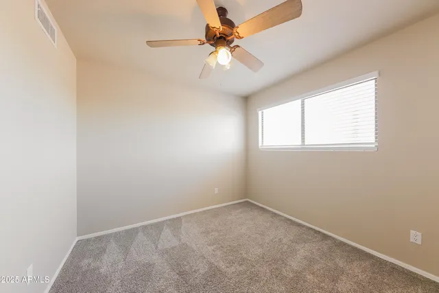 an empty room with a window and a fan