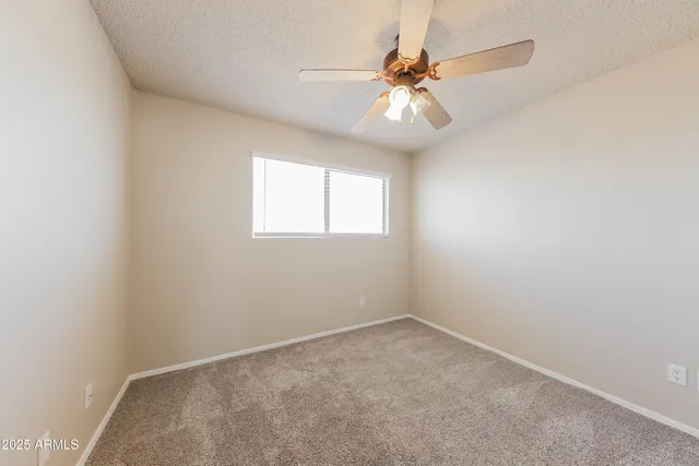 an empty room with a chandelier fan and windows