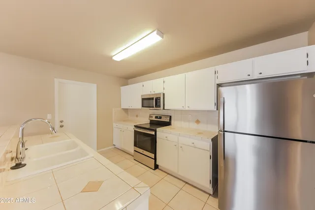 a kitchen with stainless steel appliances granite countertop a refrigerator sink and stove