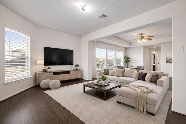 a living room with furniture a flat screen tv and a large window
