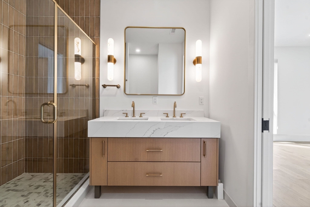 1114 Beacon Street, Unit 101 Newton, MA 02461 - Photo 14 of 29 a bathroom with a granite countertop sink a mirror and shower