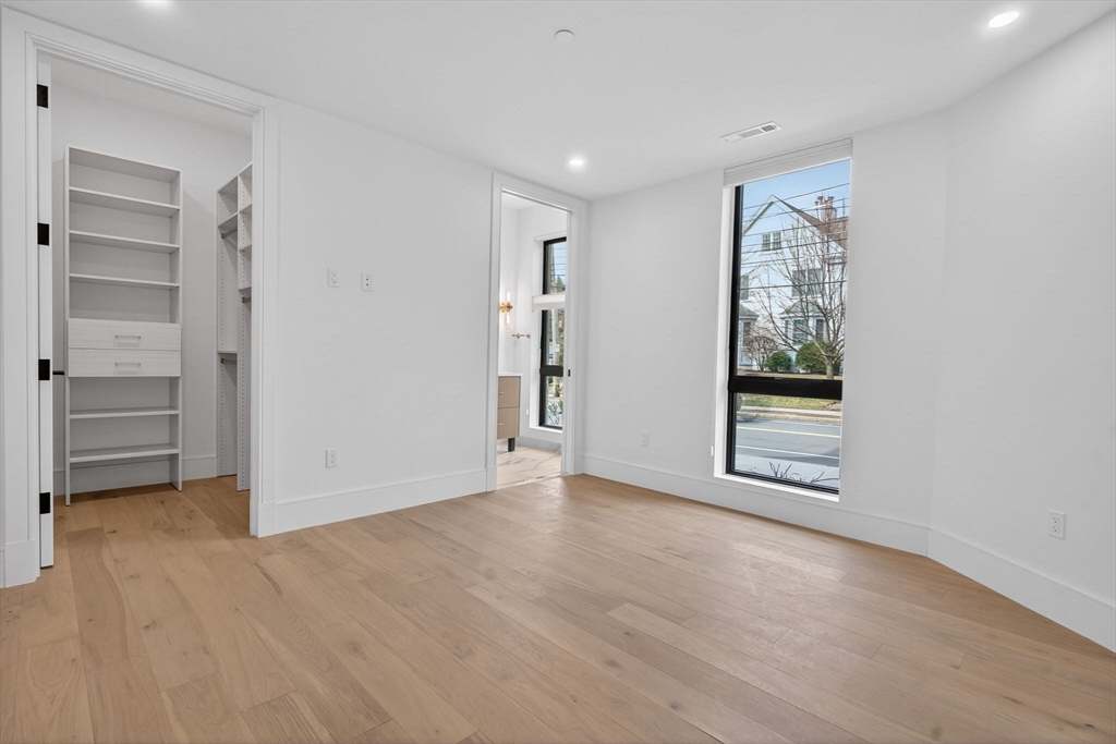 1114 Beacon Street, Unit 101 Newton, MA 02461 - Photo 17 of 29 a view of an empty room with a window and wooden floor