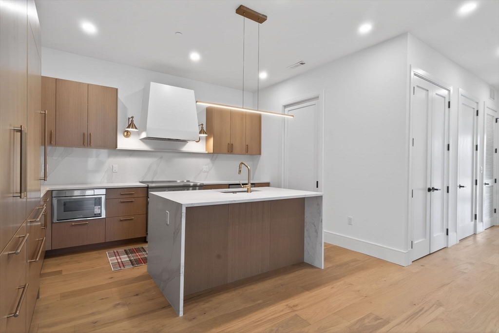 1114 Beacon Street, Unit 101 Newton, MA 02461 - Photo 9 of 29 a kitchen with stainless steel appliances granite countertop a sink stove and refrigerator