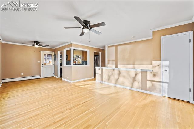 828 Valley Road Colorado Springs, CO 80904 - Photo 2 of 7 Unfurnished living room with ornamental molding, light wood-type flooring, ceiling fan, and a baseboard heating unit