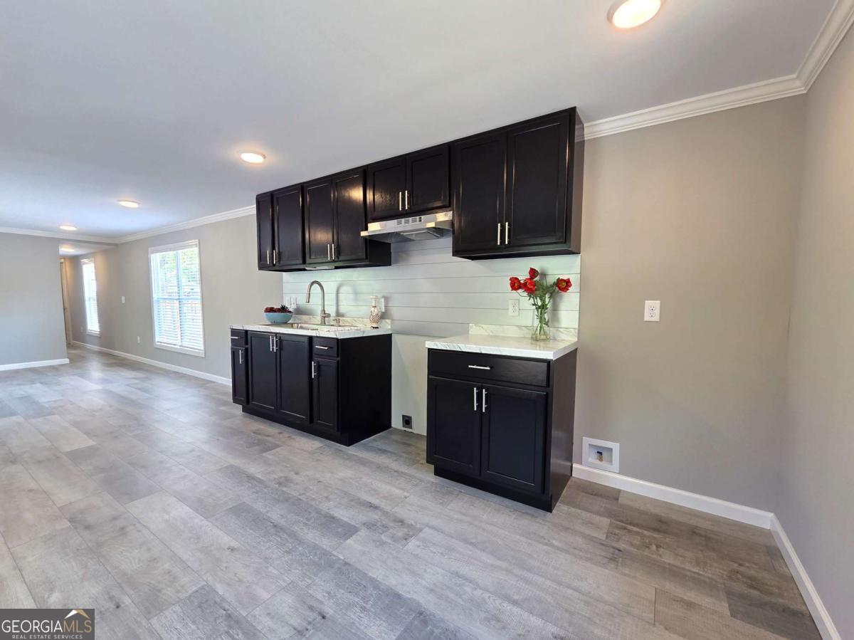 956 Donaldson Street Metter, GA 30439 - Photo 15 of 49 a room with stainless steel appliances kitchen island granite countertop a stove a refrigerator and a sink with wooden cabinets