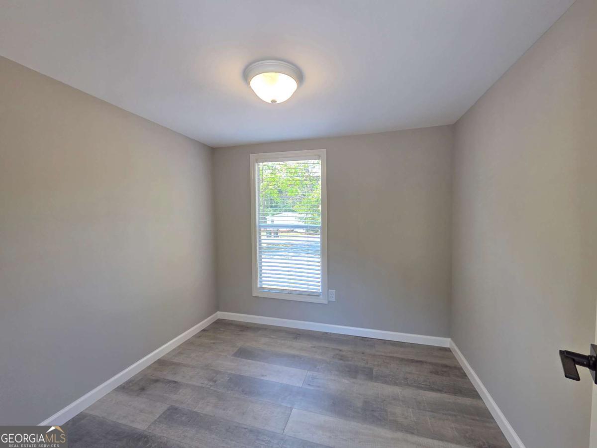 956 Donaldson Street Metter, GA 30439 - Photo 27 of 49 an empty room with wooden floor and windows