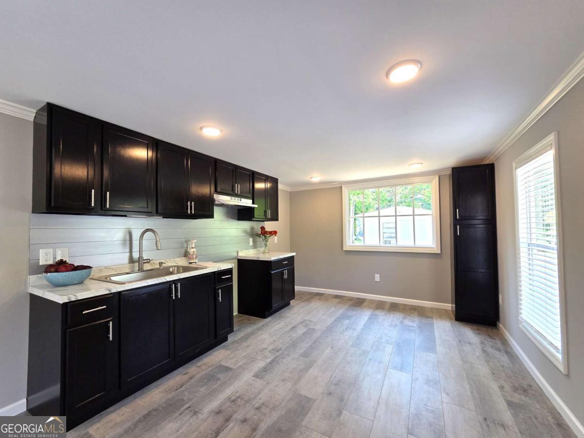 956 Donaldson Street Metter, GA 30439 - Photo 8 of 49 a kitchen with a sink wooden floor and black appliances