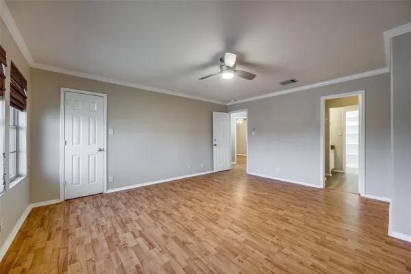 a view of empty room with wooden floor and fan