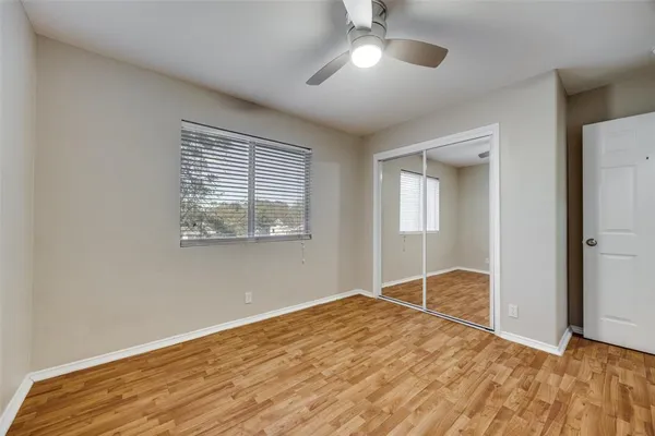 a view of empty room with wooden floor and fan
