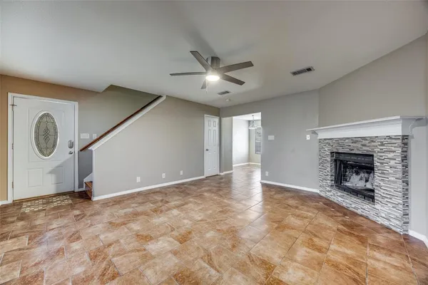 a view of an empty room with chandelier fan and fire place