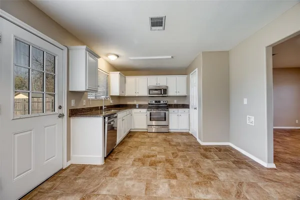 a large kitchen with white cabinets and stainless steel appliances