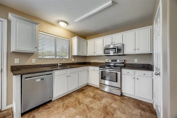 a kitchen with granite countertop a stove sink and cabinets
