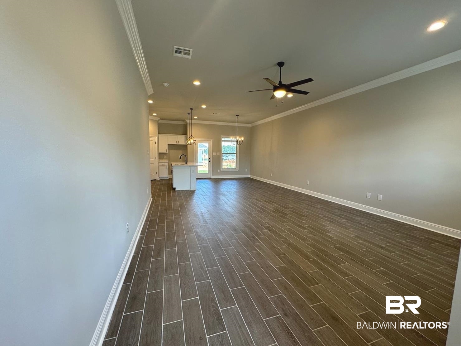 888 Sumter Loop Foley, AL 36535 - Photo 3 of 8 Empty room with sink, dark hardwood / wood-style flooring, ceiling fan with notable chandelier, and crown molding