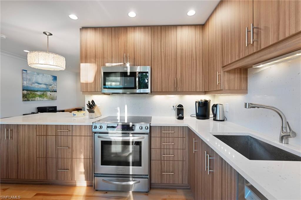 291A 8th Avenue South, Unit 291B Naples, FL 34102 - Photo 5 of 10 Kitchen with stainless steel appliances, light stone countertops, modern cabinets, pendant lighting, and a peninsula