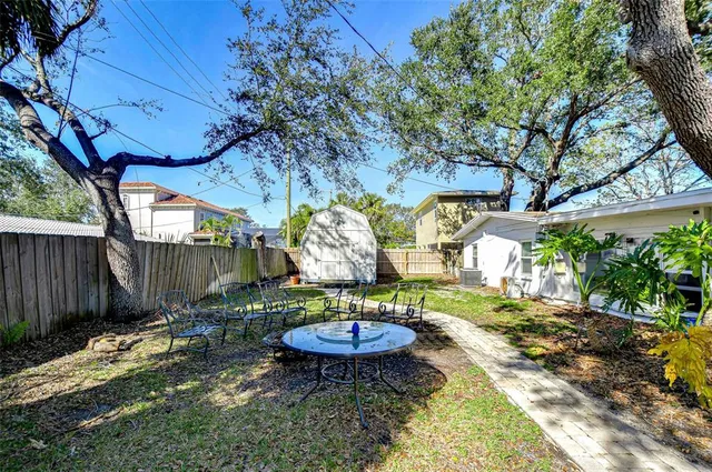 a view of a backyard with table and chairs potted plants and wooden fence