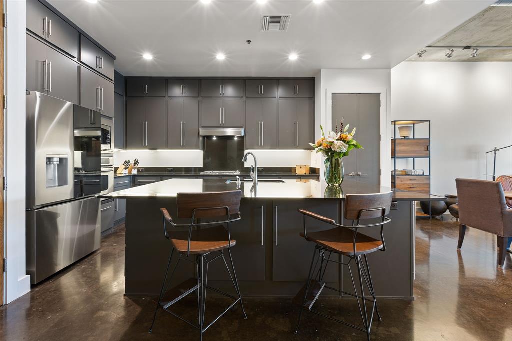3030 Bryan Street, Unit 409 Dallas, TX 75204 - Photo 6 of 30 a kitchen with granite countertop a refrigerator stove top oven and cabinets