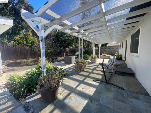 a view of a patio with table and chairs potted plants and large tree