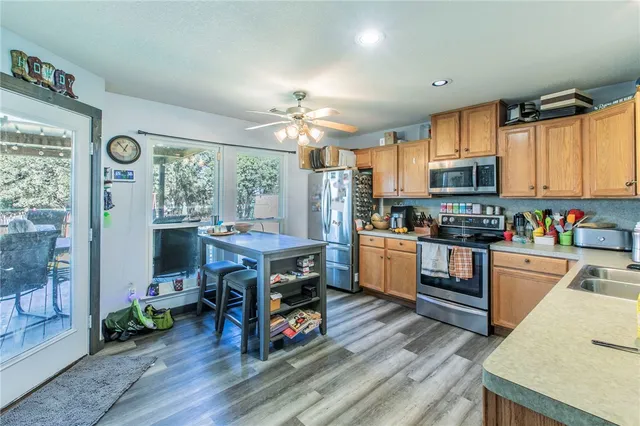 a kitchen with stainless steel appliances a stove a sink dishwasher and a refrigerator with wooden floor